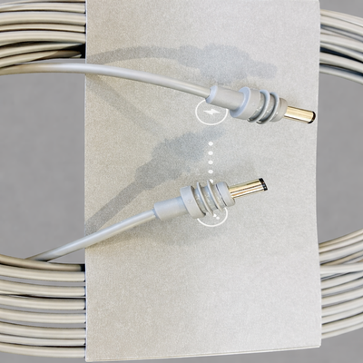 Close-up view of the Original Starlink 15-meter DC cable connectors for Starlink Mini, highlighting the metal-tipped barrel plugs and grey cardboard sleeve, with subtle product shadows on a soft grey surface